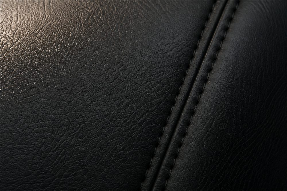 Macro view of black automotive leather grain and stitching