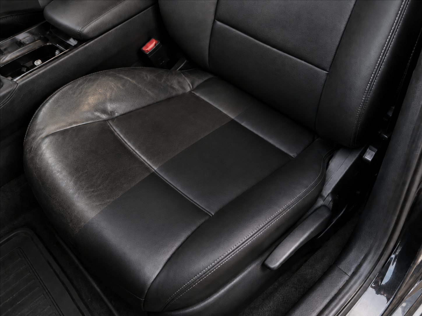 A black leather vehicle seat showing a cleaned comparison area